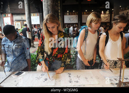 Les étudiants étrangers apprendre à écrire calligraphie chinoise au cours d'une activité au village, Shangjing Tangxi ville, dans la ville de Jinhua, East China's Zhejiang bauvin Banque D'Images