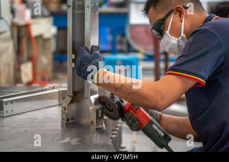 L'homme chinois travaille sur des pièces en acier inoxydable dans une usine près de Shanghai, Chine.
