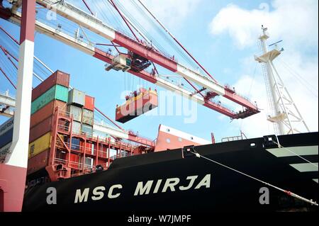 --FILE--une grue de levage du véhicule un récipient pour être expédiés à l'étranger à partir de camions sur un quai du port de Qingdao en Qingdao city, est de la Chine Shandong du pro Banque D'Images