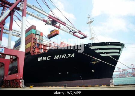 --FILE--une grue de levage du véhicule un récipient pour être expédiés à l'étranger à partir de camions sur un quai du port de Qingdao en Qingdao city, est de la Chine Shandong du pro Banque D'Images