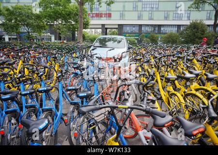 --FILE--une voiture est bloquée par des vélos à Mobike (orange), ofo (jaune) et d'autres services de partage de vélo chinois garé le long d'une route à Beijing, Chine, Banque D'Images