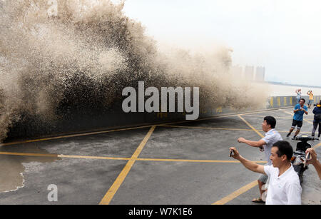 Les visiteurs et les résidents locaux regarder comme des vagues d'un mascaret montée jusqu'aux rives du fleuve Qiantang à Hangzhou City, Zhejiang Province de Chine orientale Banque D'Images