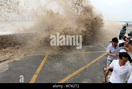 Les visiteurs et les résidents locaux regarder comme des vagues d'un mascaret montée jusqu'aux rives du fleuve Qiantang à Hangzhou City, Zhejiang Province de Chine orientale Banque D'Images