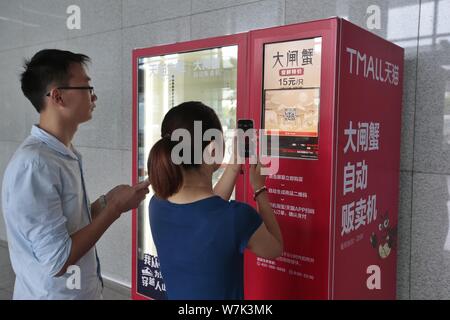 Un client chinois utilise son smartphone pour scanner le code QR sur un distributeur automatique pour acheter des crabes poilus au siège de Yiguo nourriture fraîche, un Alibaba Banque D'Images