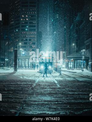 Plan vertical d'une personne devant un train sur une route enneigée Banque D'Images