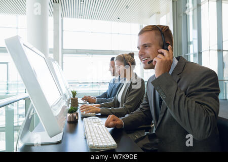 Businessman avec ses collègues talking on headset at desk Banque D'Images