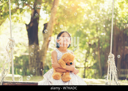 Adorable happy cute girl sitting avec ours en peluche dans le parc Banque D'Images