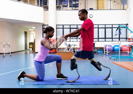 Physiothérapeute femelle aider homme handicapé à pied avec prothèse en sports centre Banque D'Images