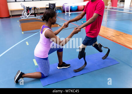 Physiothérapeute femelle aider homme handicapé à pied avec prothèse en sports centre Banque D'Images