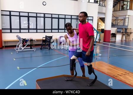 Aider les personnes handicapées à pied homme physiothérapeute avec prothèse sur la rampe d'accès au centre de sport Banque D'Images