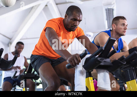 Mettre en place les hommes exerçant sur un vélo d'exercice dans le centre de remise en forme Banque D'Images