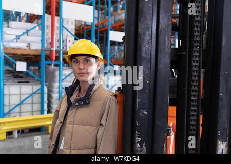 Travailleur féminin looking at camera in warehouse Banque D'Images