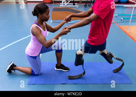 Physiothérapeute femelle aider homme handicapé à pied avec prothèse en sports centre Banque D'Images