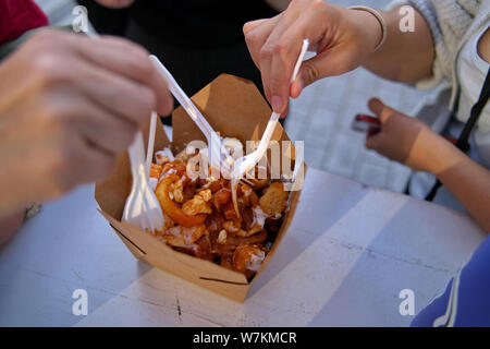 Poutine ou les frites avec de la sauce et d'autres accompagnements d'un festival camion alimentaire consommée par les visiteurs du festival de la faim. Banque D'Images