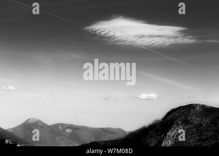 Haut de montagne sous un ciel profond, avec un nuage blanc Banque D'Images