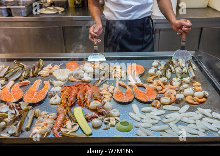 Le chef du restaurant la cuisson seafoods sur grand carré panoramique dans Cuisine Banque D'Images