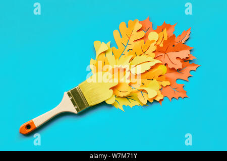 Vue de dessus sur une mise à l'aide d'un pinceau chargé de peinture en papier les feuilles d'automne. Concept accueil rénovation contexte en bleu, jaune, orange et rouge co Banque D'Images