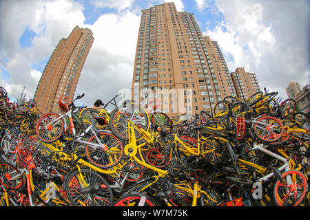 Les vélos abandonnés de Mobike (orange), ofo (jaune), Xiaoming Danche, ou Xiaoming Vélo (bleu), et d'autres services de partage de vélo chinois sont empilées jusqu'à Banque D'Images