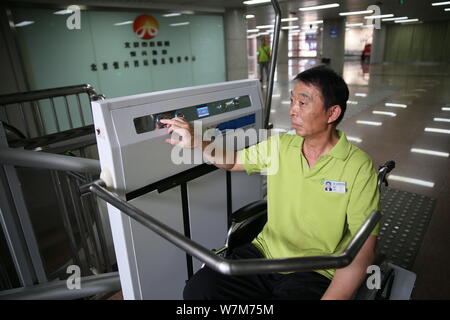 Un passager à mobilité réduite utilise la plate-forme élévatrice pour fauteuils roulants conçus pour les passagers handicapés est photographié à la sortie de la gare ouest de Beijing à Bei Banque D'Images