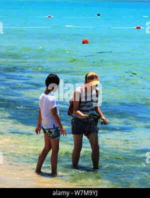 Les touristes s'amuser dans l'eau polluée avec des algues bleu-vert à un beach resort dans la ville de Sanya, province de Hainan en Chine du sud, le 21 août 2017. Banque D'Images