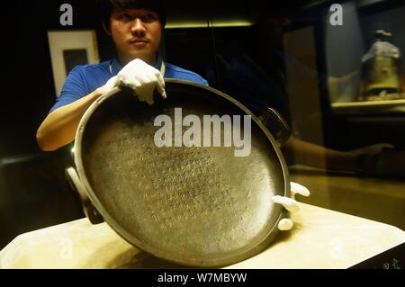 Un employé chinois affiche l 'Xi Jia pan,' une plaque de bronze de la dynastie Zhou de l'Ouest (1046¨C771 BC) vendu pour 185 millions de yuans (27,3 millions de dollars), w Banque D'Images