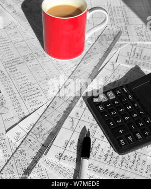 Une tasse à café rouge sur le dessus de comptes d'entreprise papiers avec beaucoup de calculs mathématiques écrit à la main sur eux, une calculatrice, tire-ligne sont également sur Banque D'Images