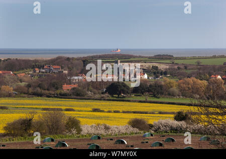 À la recherche à travers des paysages de villages de Claj et Wiveton Wiveton de Downs, North Norfolk, UK, avril 2012. L'unité porcine en libre parcours en premier plan et la mer au loin, Banque D'Images