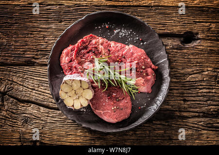 Meeat steak Faux-filet de boeuf au romarin avec du sel et du poivre sur la plaque noire Banque D'Images