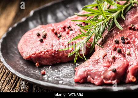 Meeat steak Faux-filet de boeuf au romarin avec du sel et du poivre sur la plaque noire Banque D'Images