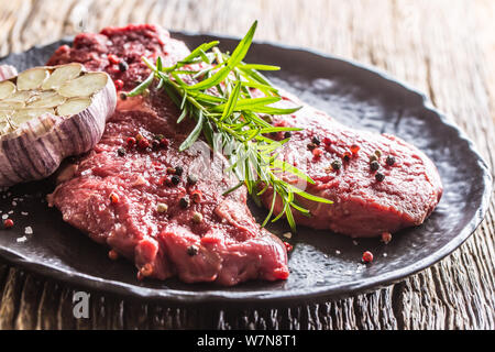 Meeat steak Faux-filet de boeuf au romarin avec du sel et du poivre sur la plaque noire Banque D'Images