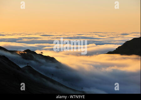 Vue sur la silhouette du télésièges et de montagnes couvertes de brume au lever du soleil vu depuis le Col du Tourmalet, Pyrénées, France, juin 2012 Banque D'Images