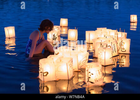 Une jeune femme veille sur des lanternes en papier dans le lac à la Toro Nagashi flottante Lanterne Cérémonie à Seattle, Washington, le 6 août 2019. "D'Hiroshima à l'espoir" est maintenu en mémoire des victimes de la bombe atomique sur l'anniversaire du bombardement de Hiroshima, au Japon. La cérémonie, organisée par un classement de la paix, les libertés civiles, religieuses et organismes du patrimoine culturel, honore les victimes des bombardements d'Hiroshima et Nagasaki, et toutes les victimes de la violence. C'est une adaptation d'un ancien rituel bouddhiste Japonais, le Toro Nagashi, lanternes dans lequel représentant les âmes des morts un Banque D'Images