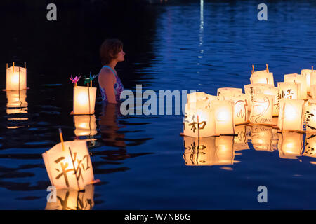 Une jeune femme veille sur des lanternes en papier dans le lac à la Toro Nagashi flottante Lanterne Cérémonie à Seattle, Washington, le 6 août 2019. "D'Hiroshima à l'espoir" est maintenu en mémoire des victimes de la bombe atomique sur l'anniversaire du bombardement de Hiroshima, au Japon. La cérémonie, organisée par un classement de la paix, les libertés civiles, religieuses et organismes du patrimoine culturel, honore les victimes des bombardements d'Hiroshima et Nagasaki, et toutes les victimes de la violence. C'est une adaptation d'un ancien rituel bouddhiste Japonais, le Toro Nagashi, lanternes dans lequel représentant les âmes des morts un Banque D'Images