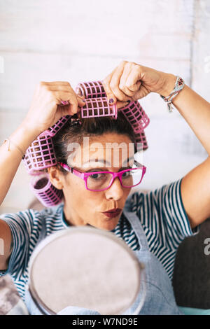 De belles personnes Nice woman at home with bigoudis sur la tête et miroir pour voir ce qui se passe - concept drôle de dame moderne à porter et ha Banque D'Images