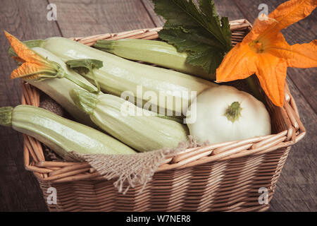Les courgettes et les fleurs sont recueillis par le jardin dans panier en osier sur fond de bois. Banque D'Images