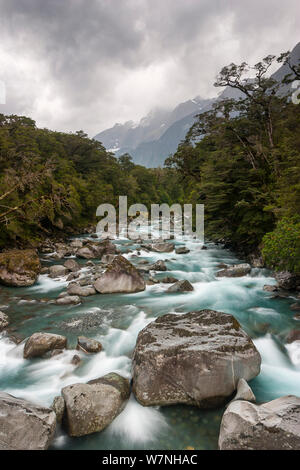 Jusqu'à la rivière de la ville historique de Tutoko pont suspendu. Les nuages orageux couvrant les crêtes des montagnes, rivière Tutoko, Fiordland National Park, Île du Sud, Nouvelle-Zélande, Février, 2005. Banque D'Images