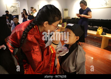 Un enseignant donne aux enfants un point rouge sur le front d'ouvrir leur "sagesse" de l'œil à la première cérémonie d'écriture dans la ville de Binzhou, East China's Beijing Banque D'Images