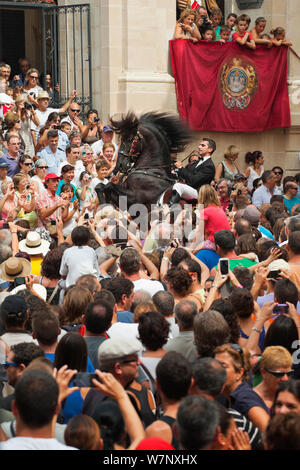 Homme monté sur un étalon Black Lagoon 52, effectuant les bot ou la marche courbette du Doma Menorquina, durant le festival Mare de Deu de Gracia, à Mahon, Menorca, Espagne 2012. Les gens essaient de toucher le cheval, qui est destiné à apporter la bonne chance. Banque D'Images