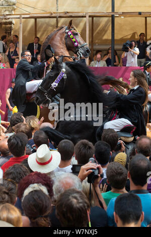 Dame sur un étalon noir Menorquin et l'homme sur un étalon andalou de châtaignier, effectuant le bot ou la marche courbette du Doma Menorquina, durant le festival Mare de Deu de Gracia, à Mahon, Menorca, Espagne 2012. Banque D'Images