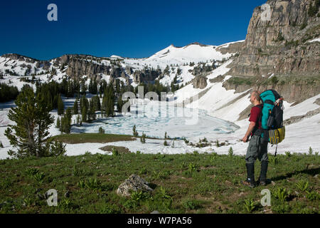 Backpacker au-dessus du lac Marion congelé le long de la Teton Crest Trail dans le Grand Teton Natoinal Park. Wyoming, USA, juillet 2011 Parution du modèle Banque D'Images