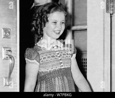 Vintage photo d'enfant américain film star Shirley Temple (1928 - 2014). La photo a été prise le 24 juin 1938 que la jeune actrice a quitté la Maison Blanche à la suite d'une réunion avec le président américain Franklin D. Roosevelt. Au cours de leur conversation, elle a dit au président comment elle avait perdu une dent la nuit avant qu'il ne tombe que lorsqu'elle a mangé un sandwich. Banque D'Images