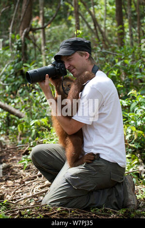 Friendly (Pongo pygmaeus orang-outan juvénile) avec photographe touristique en forêt. Nyaru Menteng Le Projet de réintroduction de l'orang-outan, le centre du Kalimantan, Bornéo, en Indonésie, en mai 2008 Banque D'Images