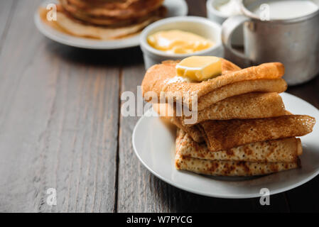 Crêpes russes blinis avec morceau de beurre sur fond de bois foncé Banque D'Images