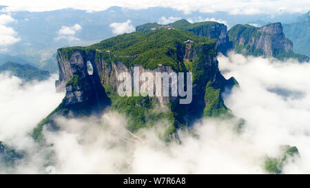 Vue aérienne de la montagne Tianmen (ou montagne Tianmenshan) entourée de nuages dans le parc forestier national de Zhangjiajie dans la ville de Zhangjiajie, central Ch Banque D'Images