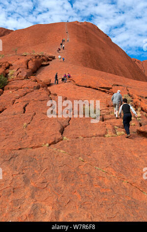 Les touristes à monter Uluru / Ayers rock, Uluru Kata Tjuta National Park, Territoire du Nord, Australie Banque D'Images