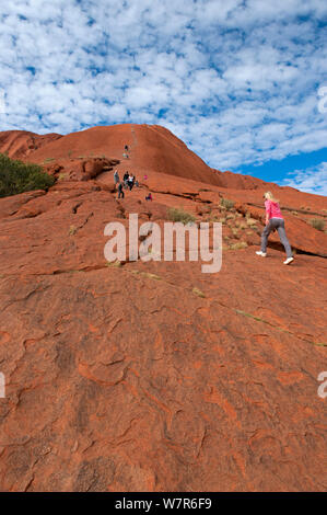 Les touristes à monter Uluru / Ayers rock, Uluru Kata Tjuta National Park, Territoire du Nord, Australie Banque D'Images