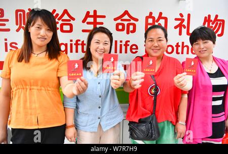 Les citoyens chinois montrent leurs cartes de donneurs de sang pour marquer le 14e jour des donateurs en face d'un don de sang à Bozhou city bus, à l'est l'Anhui Chine pro Banque D'Images