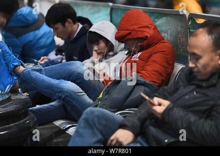 --FILE--passagers chinois qui rentrent chez eux pour le Nouvel An Chinois, aussi appelé Fête du Printemps, d'utiliser leurs smartphones pour surfer sur Internet Banque D'Images