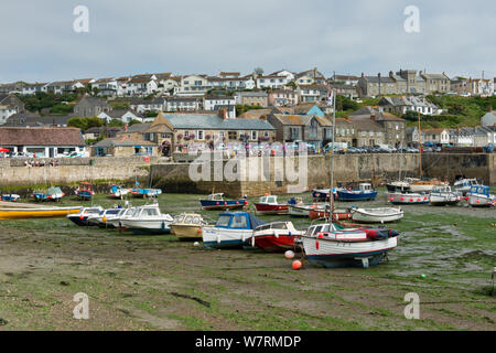 Port de Porthleven, Cornwall, Angleterre, Royaume-Uni. Reposant sur des bateaux de touristes, la boue de marée sur occupation de quayside et de maisons de ville avec vue sur le port. Banque D'Images