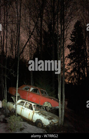 Vieilles voitures abandonnées empilés sur au sommet de l'autre en voiture 'cimetière' la nuit, avril, la Suède Bastnas Banque D'Images